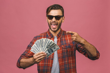 Image of shocked excited young handsome bearded man posing isolated over pink wall background holding money make winner gesture.