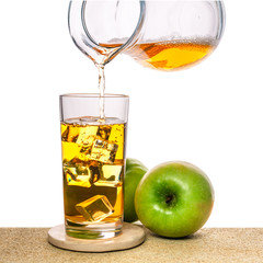 glass with ice and pouring apple juice decorated fruits on stone isolated over white background, concept of refreshing summer drink