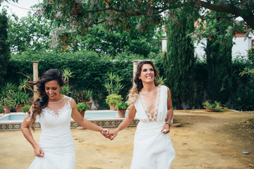 Portrait of a proud couple walking each other with white wedding dresses