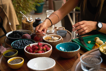 woman making smoothie bowl for breakfast. many useful fruits