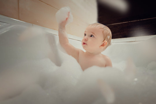 A Little Boy Is Bathing In A Bubble Bath. Cheerful Kid Playing In The Bathroom