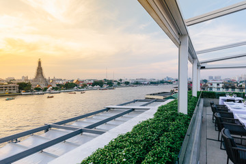 Renovated Wat Arun (The Temple of Dawn) with boats moving over Chaophraya river that view from...