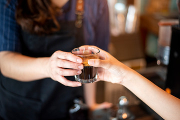 Close up of female hand is taking hot coffee from Barista
