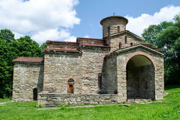 Fototapeta premium 10th century ancient Christian church, Nizhnearhizy temples, Northern Zelenchuk temple, stone temple among mountains and vegetation