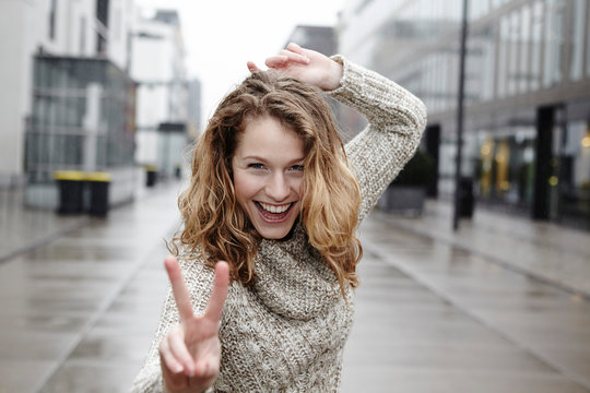 Portrait of happy young woman showing victory sign