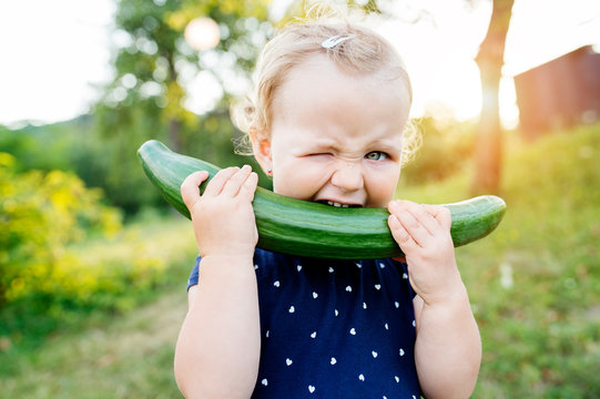 Portrait of little girl biting in cucumber