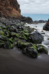 Rocks with moss and rough sea on the beach