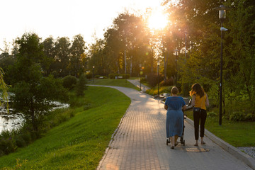 Mother and grandmother with a child in a stroller with walking in a park having quality family time 