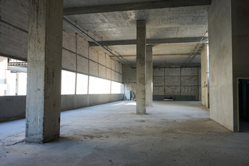 Under construction loft and raw brick rooftop at the large building with poles and tube on the ceiling.