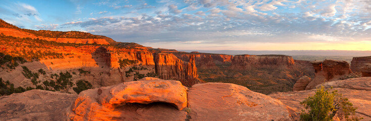 The sandstone red rock of Colorado National Monument glows under a sunrise.