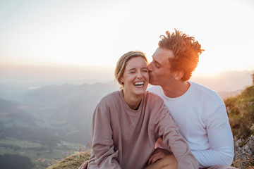Switzerland, Grosser Mythen, happy young couple on a hiking trip having a break at sunrise
