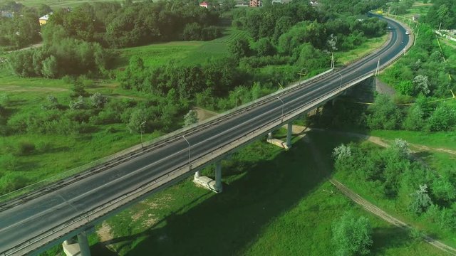 Aerial view of a busy bridge road with moving cars crossing a swamp with water and valley. 4K.