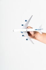 A man’s hand holding a miniature aeroplane against white background