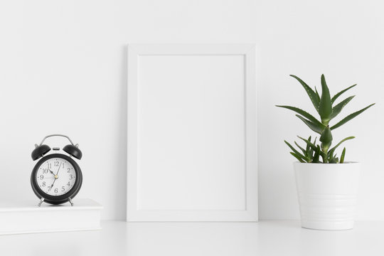 White frame mockup with workspace accessories and a aloe vera on a white table.Portrait orientation.