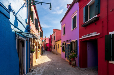 Fototapeta na wymiar bright colored picturesque buildings at a narrow street , houses of Burano in the evening