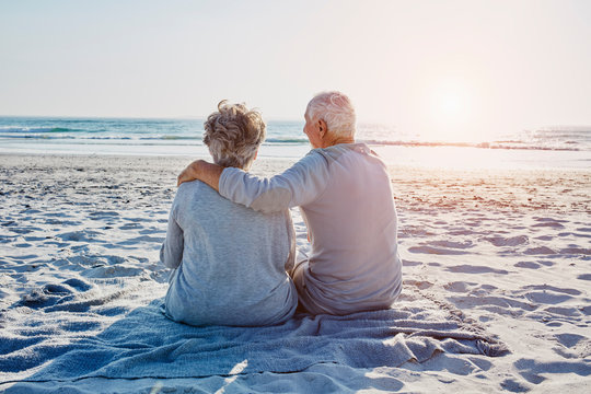 Senior Couple Sitting On The Beach Looking At Distance