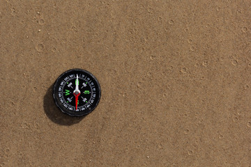 Fototapeta na wymiar Compass pointing South laying on sand beach