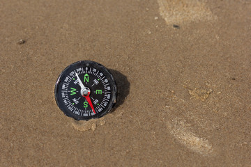 Fototapeta na wymiar Compass pointing SouthWest laying on sand beach