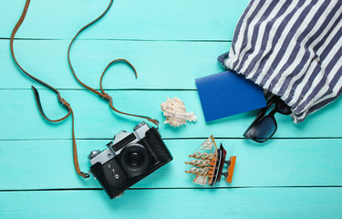 Traveler accessories, retro camera on blue wooden background. Trip on the beach, vacation. Summer minimalistic background. Flat lay tourism allegory..Top view.