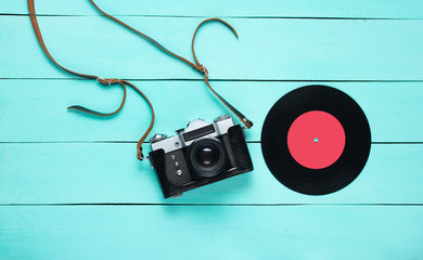 Retro still life, 70s. Vinyl record and film camera on blue wooden background. Top view. Flat lay
