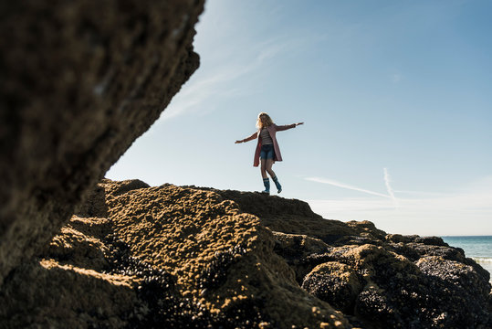 France, Crozon peninsula, teenage girl walking on rock at the coast