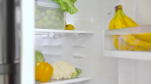 Healthy Eating, Food And Diet Concept - Female's Hand Opening Fridge With Vegetables At Kitchen