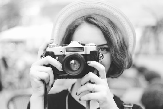 Young hipster woman holding a retro camera in her hands and taking a picture