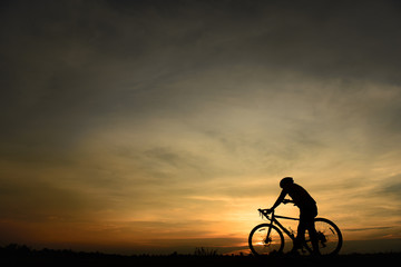 Fototapeta na wymiar Silhouette of handsome man with bicycle on sunset,sport man concept
