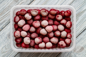 Ripe frozen red and maroon sweet cherries with hoarfrost in a plastic box. Natural organic healthy food