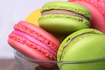 Closeup of pink, yellow, green macaroons in glass vase
