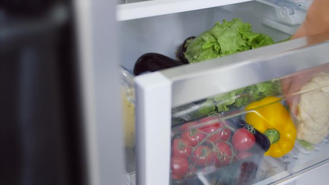 healthy eating, food and diet concept - female's hand taking cauliflower from fridge box with vegetables