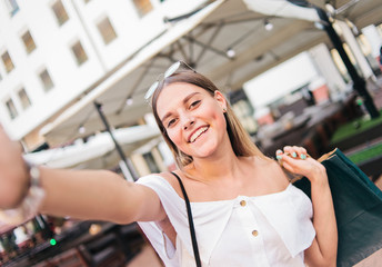 Cheerful smiling woman with shopping bags taking selfie in an urban environment