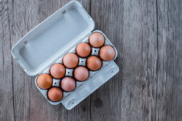 Farm chicken eggs in a cardboard box on a brown wooden background. Organic Food.