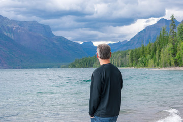 Fototapeta na wymiar Man taking in the mountain view along scenic lakeshore