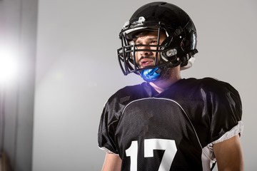 American Football player in helmet on grey with backlit and copy space