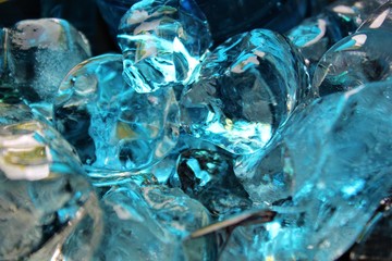 Ice cubes reflecting the frozen Arctic with teal and beige colors reflect in abstract ways within the ice.