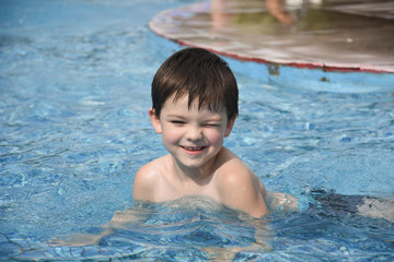 Fototapeta na wymiar Little boy play swimming and playing in the pool. Cheerful child play in the swimming pool