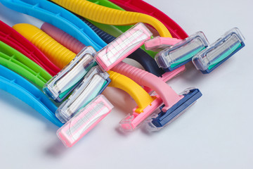Many colored plastic razors on white background close up