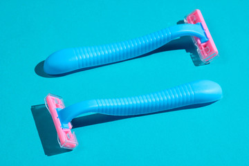 Two plastic razors on blue background. Minimalistic beauty and fashion concept