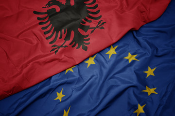 waving colorful flag of european union and flag of albania.