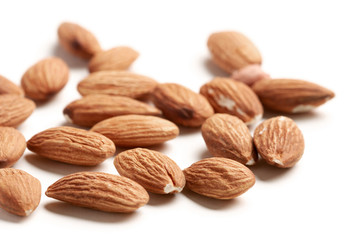 yellow almond nuts scattered on white paper background