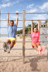 Couple training on outdoors fitness station