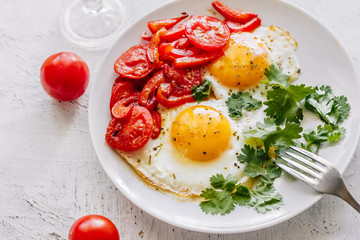 Breakfast fried eggs with tomatoes