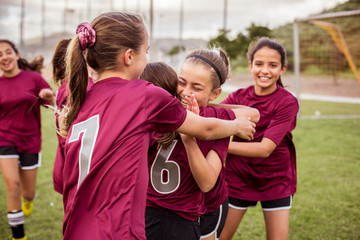 Cheerful girls embracing while celebrating success on soccer field © Cavan for Adobe