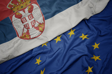 waving colorful flag of european union and national flag of serbia.