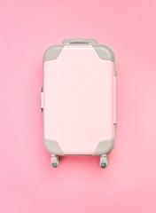 Pink suitcase on a pink background. Minimalism