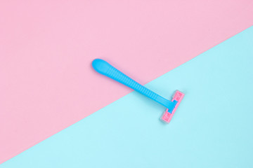 Minimalistic beauty concept. Plue plastic razor on blue pink pastel background. Top view