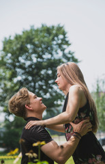 A couple of teenagers in love hugs and poses against the background of flowering trees and shrubs. Young guy and girl on the background of a blooming Park
