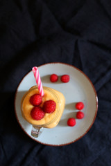 Mango and banana smoothie decorated with raspberries and reusable straw. Top view.