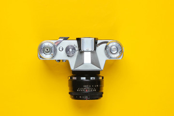 Naklejka premium Vintage retro film camera on yellow background. Top view